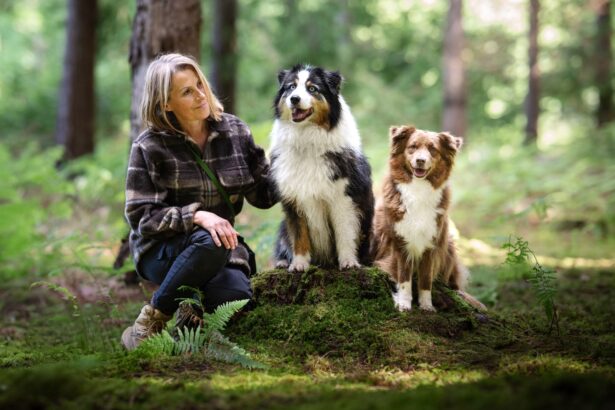 Nina Mosly assise en forêt avec 2 chiens bergers australiens
